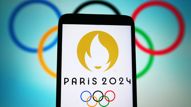 Логотип Игр в Париже на фоне олимпийских колец