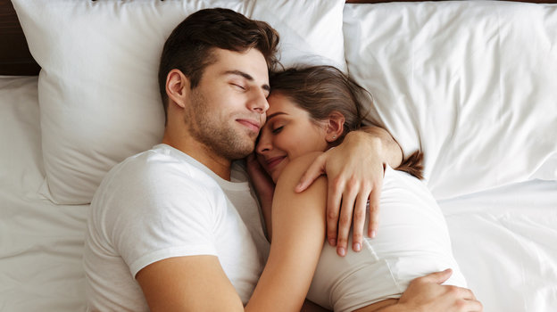 Счастливая пара лежит в обнимку на кровати
