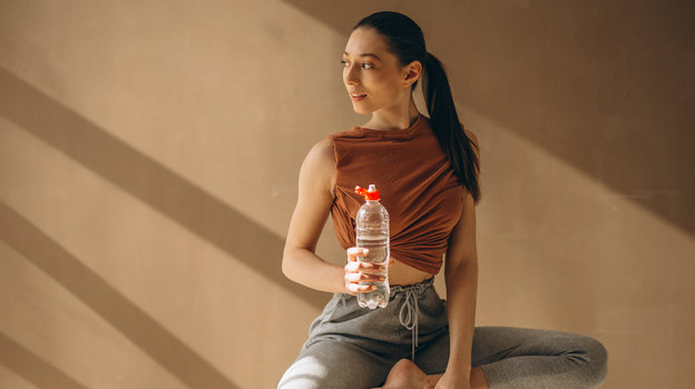 Красивая стройная девушка на тренировке с бутылкой воды