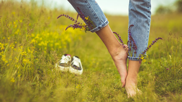 Девушка гуляет босиком по траве