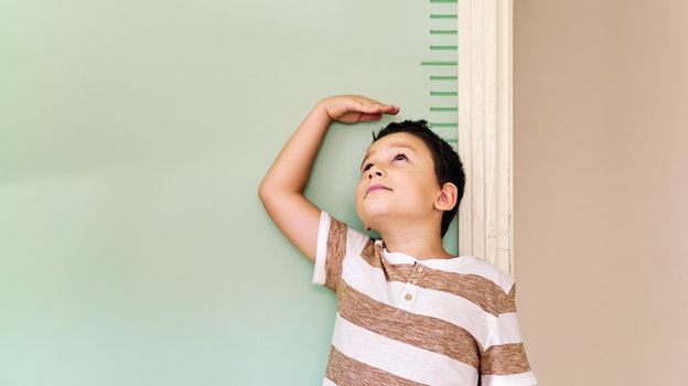 Мальчик измеряет рост у стены