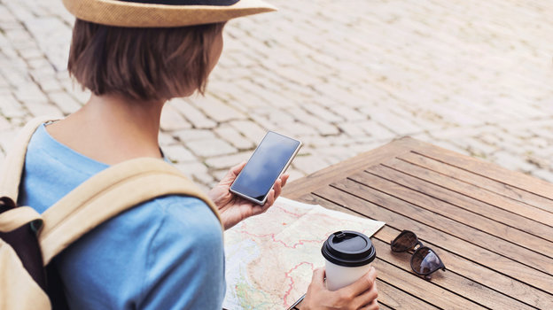 Девушка-путешественница пьет кофе и смотрит на карту