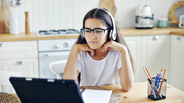 Подросток в очках сидит за компьюетром