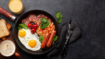 Английский завтрак с яичницей, фасолью, беконом и сосисками.