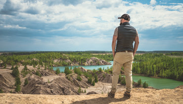Путешественник стоит на холме и смотрит вперед на красивые пейзажи